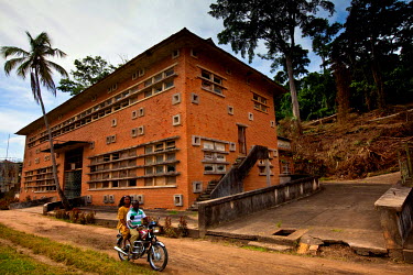 A couple on a moorbike ride past an abandoned building that was once part of the Yangambi Research Station.