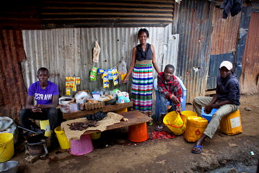 Maureen Aoko, with her sons and a cousin, on the stall where she cooks and sells food outside her one-room house in Korogocho, Nairobi's poorest slum.