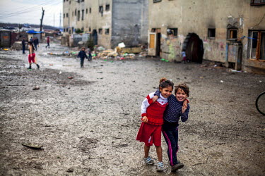Two girls walk arm-in-arm past a decrepit building in the Roma settlement on 'Budulovska Street', a segregated community where around 800 people live.