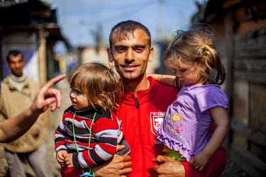 A young father with his two children in the Roma settlement located on 'Budulovska Street', a segregated community where around 800 people live.