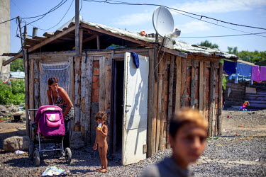 A mother an her children outside the roughly built home where they live the Roma settlement on 'Budulovska Street', a segregated community where around 800 people.