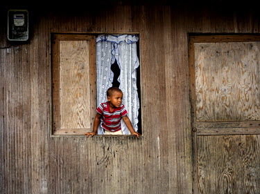 A child looks out of a house window in Puente Nayero, a slum area home to more than 1200 families. An estimated 95 percent of the residents have been forcibly displaced from their original homes due t...