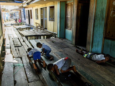 Children fishing for crabs beneath a boardwalk that runs between the houses, which are built on stilts, in Puente Nayero, a slum area home to more than 1200 families. An estimated 95 percent of the re...