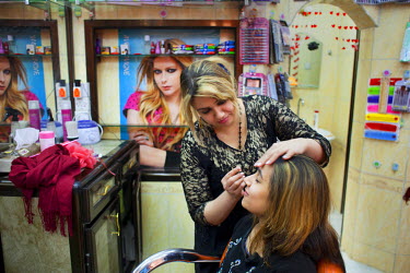 Teba Mohammed, 26, with a customer in her hair and beauty saloon, which she has restarted after her original buisness was burnt out by ISIS during their occupation of the city.