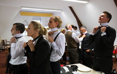 Students with their teacher learning to knot a bow tie during an intensive, eight-week butler's training course at the International Butler Academy.