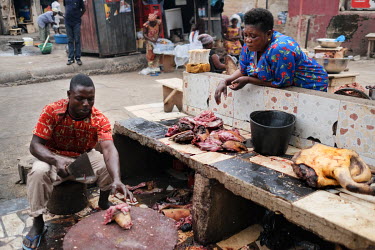 Adwoh Serwaa, a bushmeat vendor, supervising Papa Moses, a butcher, as he slices up grasscutters (greater cane rats) that she will sell at Atwemonom, the city's main bushmeat market. Bushmeat is a del...