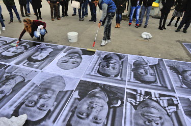 A group of asylum seekers paste portraits of refugees onto the ground at a busy intersection in the Plainpalais district of Geneva. The portraits are of people from various countries including Syria,...