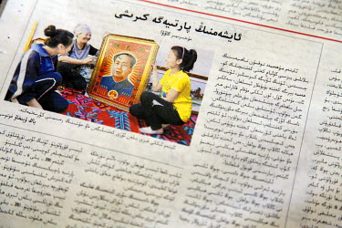 The Xinjiang Daily, a Uighur language newspaper, featuring a picture of Uighurs holding a portrait of Chairman Mao.