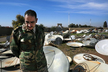 First lieutenant Naser, from the Kakai religious minority, stands among dozens of satellite dishes that had been confiscated by ISIS millitants from residents in the village of Khidr Ilyas. Behind him...