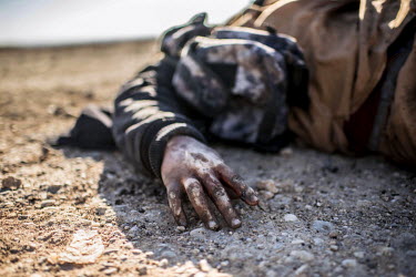 The body of an ISIS fighter killed by an airstrike lies beside a road in the village of Albu Saif.