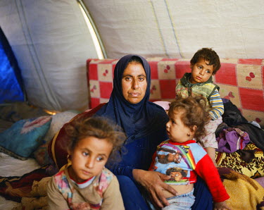 Thana Abdulah, 42, with her children inside their tent in Tinah Camp. When ISIS came to their village Thana begged her husband not to join them, said she'd rather starve, but her voice was never going...