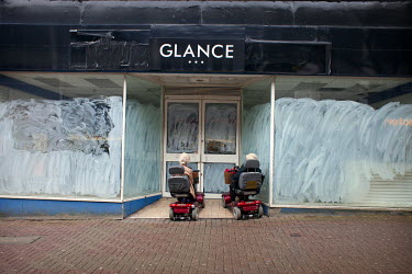 Two women on mobility scooters stopped in the doorway of a closed down shop in the Hanley area of the city.