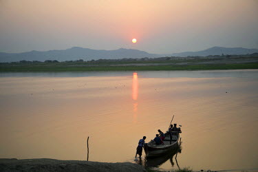 A ferry boat moored on the banks of the Irrawaddy River at sunset.