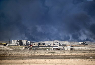 Smoke rises from oil wells set on fire by ISIS in late 2016 which continue to burn.