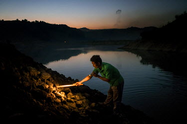 Freelance miners scavenge for jade rocks using torchlight as the discarded tailings from Hmaw Si Sar Mine are dumped from trucks.
