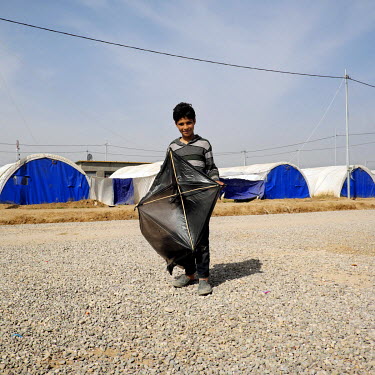 Fahad, a ten year old IDP boy from Mosul, poses with his homemade kite, fashioned out of a plastic bag, at the Al-Khazer IDP camp where he has been with his family for less than two weeks.