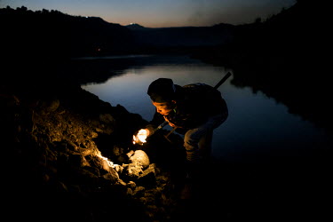 Freelance miners scavenge for jade rocks using torchlight as the discarded tailings from Hmaw Si Sar Mine are dumped from trucks.