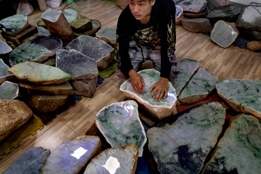 A worker marks out bracelet sized circles on jade rocks in a jade company showroom near the Mandalay Jade Market.
