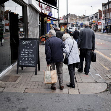 An elderly couple look at a cafe's board advertising a breakfast meal in Palmers Green.