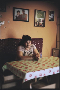 A Roma woman sits at a table in her home.  A 28 year old father and his four year old son from her community were murdered by neo-nazis who used a machine gun to shoot them after throwing a Molotov co...