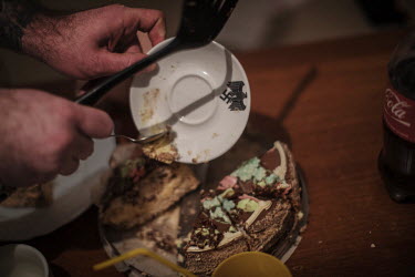 Neo-nazi Evgenij Stojka clears the dishes, decorated with nazi insignia, after eating cake in his home in the outskirts of Kiev where he lives with his wife and daughter. 'I got interested in the nazi...