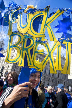 A woman carries a sign made up of cut-out letters that annouces: 'Fuck Brexit' at a 'Unite for Europe March on Parliament'.