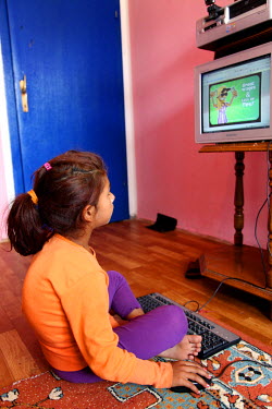 A Roma girl, diagnosed with scoliosis, playing a computer game at her home in a Roma district of the city.