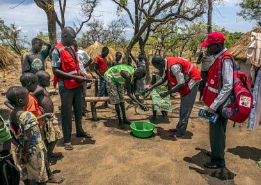 A team of volunteer Hygiene Promoters for the Red Cross demonstrate good hygiene and sanitation to a family of South Sudanese refugees in Bidibidi camp.