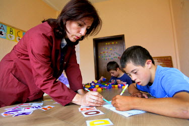 A teacher helps a child, who has physical and learning disabilities, write during a lesson at the Lefnosi School.