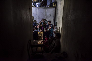 Families look up anxiously while they hide in a basement as fighting between ISIS militants and pro-government forces rages above them on the front line in the al Thawra neighbourhood of western Mosul...