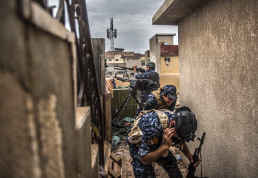 Two men take cover as a member of the Federal Police force fires at ISIS positions on the front line in the Bab Ajdiid neighbourhood of western Mosul.