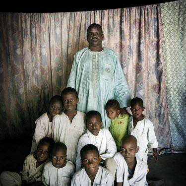Al Haj Boukar, 46, with eight of his sons and daughter in Maroua.   Boukar was a wealthy business owner who fled the conflict and is now plunged into poverty with his family of eleven, including his m...