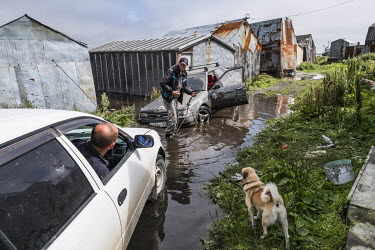 Sergey and his friend trying to tow his car out of a flooded area on the sea front. Flooding occurs regularly, sometimes cutting off road access to the settlement. Since the 1970s the sea has been cla...
