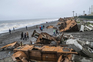 Workers from the local fish processing factory, 'Narody Severa', walking on the eroded beach. To avoid further disappearance of the land the management of the factory has placed concrete blocks from d...