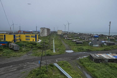 Sleek wind turbines contrast with the tatty buildings of the Oktyabrskiy, located on a sand bar between the Sea of Okhotsk and Bolshaya River. Since the 1970s the sea has been claiming the land, destr...