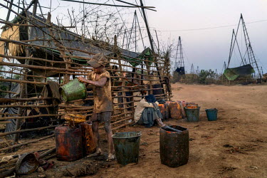 La Pyae, 12, scrapes oil, she has scavenged from spillages, from one bucket into another at the Nga Naung Mone, Myanmar's largest unregulated oil field. Pyae can usually find enough oil each day to fi...