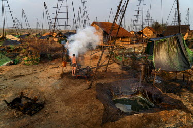 A wildcat oil propector starts a generator to power a winch that he will use to draw oil from below the ground at Nga Naung Mone, Myanmar's largest unregulated oil field.