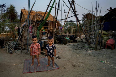 Children of wildcat oil prospectors stand on a mat in front of their home and the family's makeshift derrick on Dagine oil field.