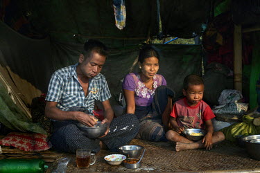 A family who are wildcat oil prospectors eat breakfast in their hut next to their makeshift oil derrick on Dagine oil field.