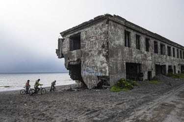 A group of teenagers riding bicycles on the beach next to a derelict apartment block in the so-called 2nd Base, an area of Oktyabrskiy that is heavily affected by coastal erosion.  Since the 1970s the...
