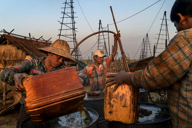 Workers fill barrels with oil from wildcat prospector's drill sites on Nga Naung Mone, Myanmar's largest unregulated oil field.