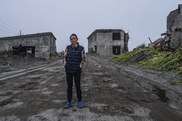 Inessa Kondrashkina standing on a road in the 2nd Base of Oktyabrsky, an area heavily affected by costal erosion. Since the 1970s the sea has been claiming the land, destroying part of the settlement....