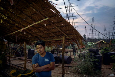 A wildcat oil prospector at Nga Naung Mone, Myanmar's largest unregulated oil field, rests against his hut after a day's work drilling for oil.