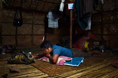 A wildcat oil prospector watches a video on his smartphone as he rests in his hut after a day's work at Nga Naung Mone, Myanmar's largest unregulated oil field.