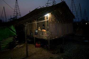 A woman sits with a child in their home in the Nga Naung Mone, Myanmar's largest unregulated oil field.