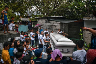Friends and family help carry the coffin of Raphael Cruz, 28, at his funeral in Manila North Cemetery.