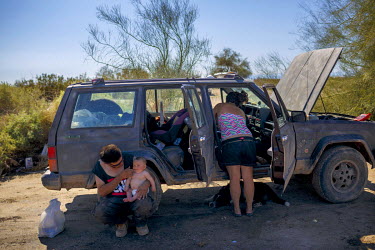 Derek feeds his baby while his partner, Shay organises the inside of the car that is their living space at Slab City, a squatters' camp about 190 miles southeast of Los Angeles.   Slab City, known as...