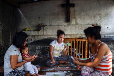 Residents of Manila North Cemetery play cards in a mausoleum. Manila North Cemetery is home to thousands of 'informal settlers' who have built shacks using in and around the mausoleums, crypts and tom...