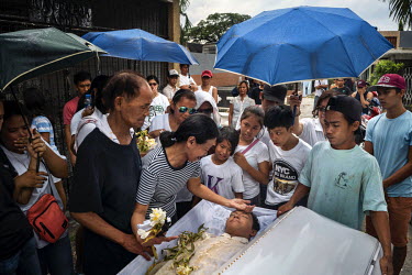 Family and friends pay their final respects before the coffin of Glen Balena, 26, is interred at Manila North Cemetery. Manila North Cemetery is home to thousands of 'informal settlers' who have built...
