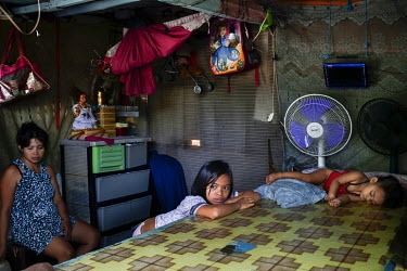 Rachael Canaveras 10 (centre) rests with her sister, Eliza, one, on the tomb that their shack is built over. Their mother sits beside them in Manila North Cemetery.  Manila North Cemetery is home to t...